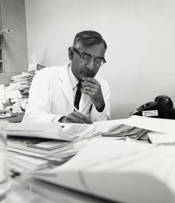 Professor Har Gobind Khorana, who taught biochemistry at the University of Wisconsin-Madison from 1960 to 1970, sits at a desk full of papers